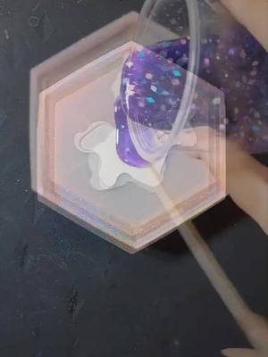 A post by @resinating_art on TikTok caption: #unicorn #coaster #epoxy #resin #art #purple #glitter #holographic #sticker #resinmold #demolding #resinpour