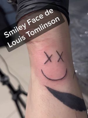 A post by @aominemarj on TikTok caption: Smiley face de Louis Tomlinson :) #tattoo #tattoolearning #fyp #drawing #tatuaje #tatuando #aprendiendoatatuar #louistomlinson #louis #tommo #smiley #smileyface #faithinthefuture #walls #onedirection #1d #1direction #autotattoo #autotatuaje #cromos #smalltattoo 