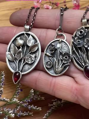 A post by @thlaylidesigns on TikTok caption: My new spring, Persephone-inspired collection is dropping in T-minus 30 minutes! Head over to my shop, link in bio #silversmith #metalsmithing #jewelry #artistsoftiktok #witch #pomegranate #persephone #daffodil #slowcrafts 