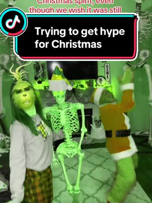 A post by @thathalloweenfamily on TikTok caption: Time to bring out the Grinch costume and make Mr. & Mrs. Skelly Claus! 🖤💚🖤 #missinghalloween #grinchmas #thegrinchtiktok #skeletonchristmas #halloweeneveryday 