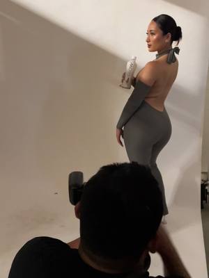 A post by @asiabanyaga on TikTok caption: behind the scenes of my grey jumpsuit shoot ft. @GLOW Beverages #GLOWHydration #GLOWPartner #DrinkGLOW #LetsGLOW