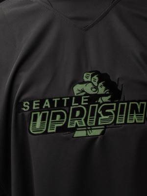 A post by @uprisingpaintball on TikTok caption: Introducing the Seattle Uprising 2024 World Cup Jersey, possibly the worlds first embroidered Glow In The Dark paintball jersey 🤯  Available now, including fully custom options with your name & number 🙌 Your support helps us continue to stay an independently owned & operated team, and we are grateful to have you in our corner 🩶 #paintball #propaintball #nxl 