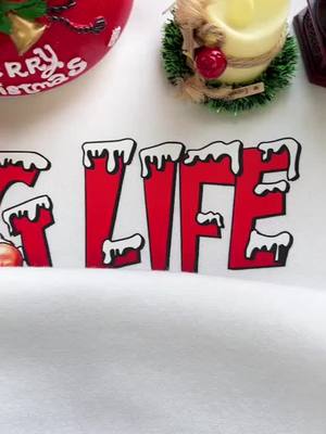 A post by @printleast.com on TikTok caption: Cozy up for the holidays with our Christmas Life T-shirt. Shop now.