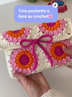 A post by @hellohanae on TikTok caption: Le tuto de la pochette à livre au crochet est là !!! Qui va la faire ? 🤭  Je vous prépare la version Ytb ultra détaillée et débutant friendly 💖 Tuto pochette à livre au crochet, soit le cadeau de Noël parfait à offrir à ceux qui aiment lire ⭐️ Tuto carré granny fleur :  @Hanaé 🌸 crochet & co  Coudre des carrés :  @Hanaé 🌸 crochet & co  Les mailles serrées : @Hanaé 🌸 crochet & co  #crochet #crochetersoftiktok #crochetgift #pochettealivre #christmascrochet #cadeauxdenoël #tutocrochet #crochettutorial #grannysquare #booksleeve 