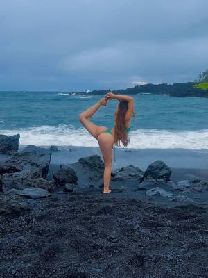 A post by @lauramejiayoga on TikTok caption: Black sand beach 🖤 #yoga #hawaii #maui #beach