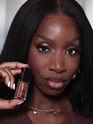 A post by @cocoaswatches on TikTok caption: trying the new @e.l.f. Cosmetics glimmer lip oil in chocotease ✨ do we love 👀 #cocoaswatches #darkskinmakeup #blackgirlmakeup  Elf glimmer lip oil chocotease on dark skin 