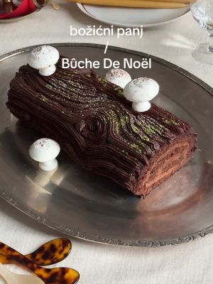 A post by @ivo_zinee on TikTok caption: Božićni panj / Bûche De Noël (recept u opisu!) punjen kremom od mascarponea i Nestle dessert tamne čokolade s glazurom od čokoladnog ganachea i Čola. 🌲💫🕺🏻 RECEPT: biskvit: 6 jaja (M veličina), razdvojenih 160g brašna 2 žlice kakaa 1/2 žličice soli 200g šećera (podijeljeno na pola) 2 žlice ulja 1 žličica praška za pecivo malo ekstrakta vanilije maslac za podmazivanje punjenje: 80g tamne Nestle čokolade 180g (100g + 80g) vrhnja za šlag 125g mascarponea sobne temperature glazura: 150g tamne Nestle čokolade 150g vrhnja za šlag gljive od meringe: 2 bjelanjca (sobna temperatura) par kapi limunovog soka prstohvat soli 100g šećera kakao prah (po želji) POSTUPAK: Pleh namastiti, a zatim prekriti pek-papirom koji ćete također lagano namastiti. Pomiješati i prosijati brašno, prašak za pecivo i sol. Odvojiti bjelanjca i žumanjca, a zatim tući žumanjca, 100g šećera dok ne posvijetle i poveća im se volumen. U čistoj posudi tući bjelanjca dok ne zapjene, a onda postepeno dodavati 100g šećera dok ne dobijete čvrstu meringu. Polako sjediniti smjesu od žumanjaca i bjelanjaca pazeći da ne miješate jako. Zatim dodati suhe sastojke i laganim pokretima sjediniti.  Smjesu uliti u kalup i staviti u prethodno zagrijanu pećnicu na 180 stupnjeva na 10-12 minuta. Paziti da se ne prepeče.  Napraviti punjenje tako što ćete 80g tamne čokolade preliti s 80g vrućeg vrhnja za šlag, pustiti da odstoji par minuta, a zatim umiješati u ganache. Sve to ćete uliti u umućenih 100g šlaga i mascarponea te sjediniti.  Biskvit izvaditi iz pećnice, lagano natopiti vrućim mlijekom s kakaom, preokrenuti na papir (ili krpu) koju ste posuli kakao prahom, kad je biskvit još mlak premazati nadjevom i zarolati. Čvrsto stegnuti i ostaviti u hladnjaku 2-4 sata ili preko noći.  Napraviti ganache za glazuru tako što ćete prokuhati vrhnje za šlag i preliti preko nasjeckane čokolade te izmiješati u jednoličnu smjesu.  Za gljive od meringe ćete čvrsto umutiti bjelance sa šećerom, soli i limunovim sokom, na pek papir raditi kape i stapke, a zatim sušiti na 80 stupnjeva nekih 2 sata. Posuti kakao prahom i spojiti uz pomoć malo ganachea.  Ukrasiti tortu i poslužiti.  #HolidayDessertIdeas #NestleDessert #yulelog #bozicnipanj #buchedenoel #chocolate #cokolada #balkan #hrvatska #bosna #dessert #baking #zdravkocolic #christmas