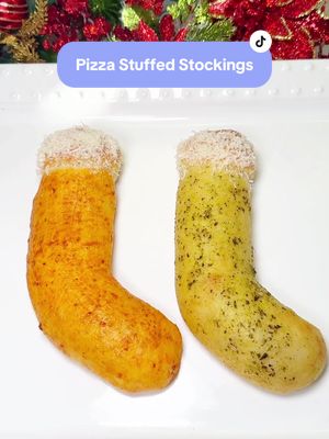 A post by @chefgenevieve on TikTok caption: Pizza Stuffed Christmas Stockings! 🍕🎅 Inspired be Santa’s Ways on @Cafe Casino  Ingredients: 1 can pilsbury pizza dough sheet 6 Tbsp marinara 6 Tbsp shredded mozzarella cheese Butter Parmesan cheese (Optional) 2 tsp pesto for added color (Optional) 2 tsp marinara for added color Directions: Roll out a sheet of pizza dough. Use a rolling pin to widen the surface area if needed. Cut into three even rectangle sections then cut an inch strip off from the top.  To each section, spread on 2 Tbsp marinara then sprinkle on 2 Tbsp shredded mozzarella cheese. Gently roll over to seam side down. Pinch the bottom together, cut off any excess dough then tuck underneath. Repeat the same process for the top. Move the bottom half to the side to resemble the shape of a Christmas stocking.  Wrap the extra dough strips around the top and tuck under.  Optional: brush on some marinara and/or some pesto to add festive colors. Bake in a 400°F oven for 14 minutes or until  golden the brush on melted butter and grate on Parmesan cheese for the furry top effect.  Enjoy! #ChristmasRecipe #PizzaStuffedStockings #FunChristmasRecipe #FestiveRecipe #CafeCasinoPartner