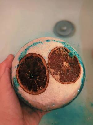 A post by @kinkbombsllc on TikTok caption: "Escape to the Grand Line 🏝️✨ Our Nami-inspired bath bombs are the ultimate relaxation treasure—tropical scents and dried tangerine for that perfect island vibe 🌊🍊 Treat yourself, captain! #SenpaiSuds #OnePieceVibes #BathTimeGoals"