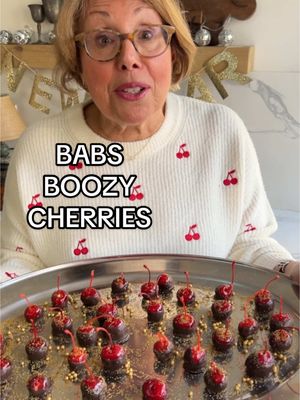 A post by @brunchwithbabs on TikTok caption: 🍒 BABS BOOZY CHERRIES  🍒 Soaked in rum, dipped in chocolate, and ready to elevate your New Years Eve party! Sweet, boozy, and oh-so-irresistible, you won’t be able to have just one… INGREDIENTS: Maraschino Cherries Spiced Rum  Candy Melts  Glitter Sprinkles  INSTRUCTIONS: Drain your cherries and cover with some spiced rum (you could even use bourbon). Refrigerate for at least four hours. For extra boozy cherries, you can leave them in the fridge overnight. When the cherries are done marinating in the spiced rum, remove the cherries and let them dry on a paper towel. Microwave your candy melts (you can use milk chocolate or dark), and make sure you melt in 30 second intervals. The chocolate should be ready in about a minute and a half. Dip each cherry by its stem in the chocolate, and immediately decorate with sprinkles. Happy New Year! 🥂 #newyearseve 