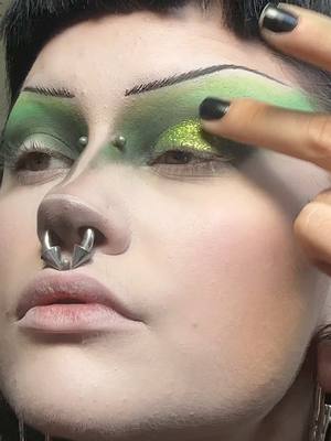 A post by @motherof.hades on TikTok caption: soooo i love green 💚 a lot a lot! looove how big & draggy this came out 🫦  @𝔇𝔯𝔬𝔭𝔇𝔢𝔞𝔡𝔊𝔬𝔯𝔤𝔢𝔬𝔲 @NYX Professional Makeup @Black Moon Cosmetics  #goth #gothmakeup #gothsubculture #motherofhades #facepiercings #foryou #fyp #trending #tradgoth #tradgoth #green #greenmakeup #greenmakeuplook #greenmakeuplook💚 #dragmakeup #stretchedseptum #bridgepiercing 