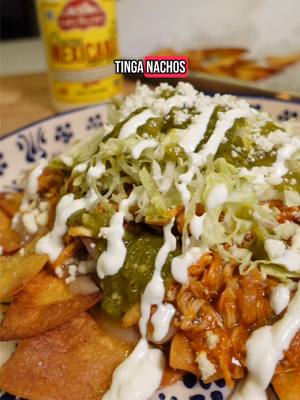 A post by @pizcitadesal on TikTok caption: Tinga Nachos #tinga #mexicanrecipe  For the Tinga: 4 roma tomatoes 1 small chunk of onion (for the sauce) 2 garlic cloves ½ small can of chipotle in adobo (about 7 oz) 1.5 tbsp consommé de pollo ½ tsp oregano 1.5 cups water 1 rotisserie chicken (shredded, skin removed) Oil (for cooking) ½ white onion (sliced, for sautéing) Black pepper (to taste) 1 cup cilantro (chopped) For the Nachos: Tortilla chips Refried beans Queso fresco (crumbled) Shredded lettuce Salsa verde Mexican crema