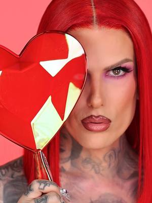 A post by @jeffreestar on TikTok caption: Paint the town RED!💋 Getting ready to SLAY this Valentine's Day with another #iconic Jeffree Star makeup tutorial ❤️ #makeup #jeffreestar #beautytips #redlipstick #fyp #BeautyTok #foundation #valentinesmakeup  Makeup by: @Lipsticknick  Hair by: @Jay  Video by: @jacqueline.j  Products Used ⤵️⁠ Crystal Heart Hand Mirror 'Red' 'Black'⁠ Wyoming Winter Recovery Face Oil⁠ Morning Dew Hydrating Eye Cream⁠ Lollipop Killer Artistry Palette BeachProof Eyeliner 'Gothic Beach'⁠ BeachProof Mascara⁠ Magic Candy™ Liquid Blush ‘Hollywood Sucker’⁠ Magic Candy™ Color Corrector 'Candy Youth' 'Diet Peach'⁠ Magic Star™ Luminous Setting Powder ‘Pink Cashmere’⁠ Skin Frost™ Highlighting Blush⁠ 'Glamorous Heist'⁠ Velvet Trap 'Diet Mannequin'⁠ Liquid Lip Balm 'Redrum'⁠