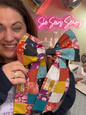 A post by @shesewsseams on TikTok caption: I’m in my patchwork era right now.  And thanks to @Ruby Star Society I was able to combine that with my BOW era.. I love it when a plan comes together! Check out their “Pivot Patchwork Bow” tutorial to make one of your own!! #patchwork #bowseason #sewingdiy #scrapbuster #sewingforbeginners #learntoquilt 