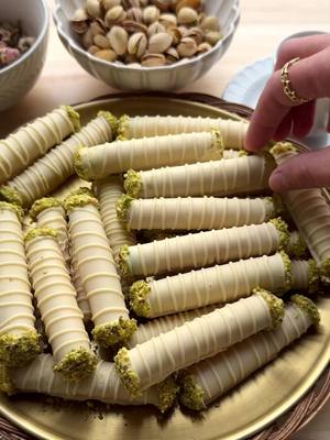 A post by @kookmutsjes on TikTok caption: PISTACHIO CIGAR COOKIES WITH WHITE CHOCOLATE #food #recipe #morocco #maghreb #cookies #pistachio #chocolate #nobake #eid #eid2025 #ramadan  COOKIES cigar cookies FILLING pistachio paste COATING 300 g white chocolate GARNISH white chocolate pistachios (unsalted)