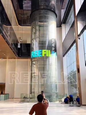 A post by @reefilm_display on TikTok caption: A perfect blend of technology and beauty! The LED flexible transparent film screen brings a new visual experience to glass sightseeing elevators -high transparency, seamless integration, and a futuristic, unobstructed view  #ledfilm #panel #china #ledwall #install #transparent #hottest #leddisplay #reefilm #ledscreen #glass 