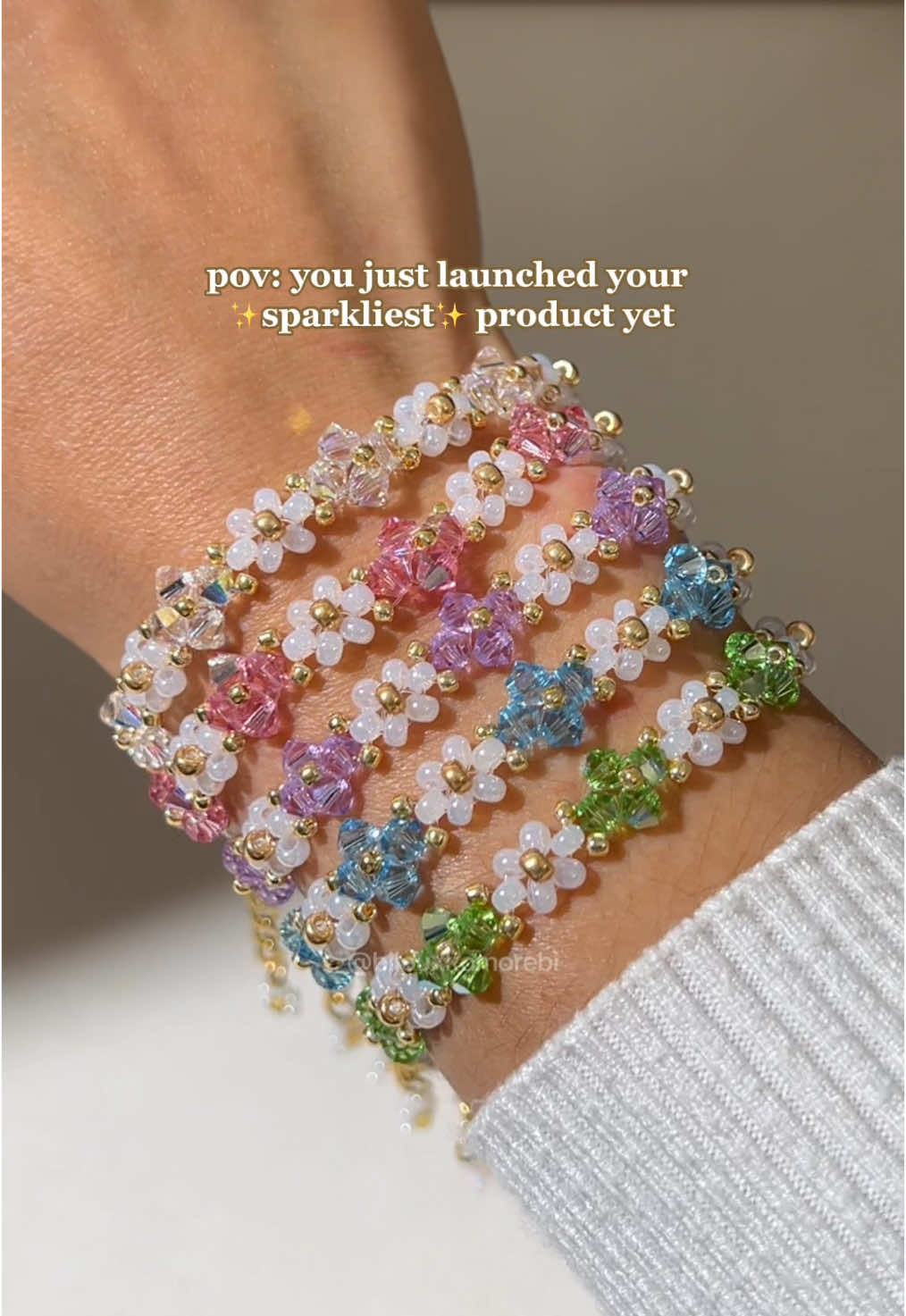 A post by @bijouxkomorebi on TikTok caption: ⭐️ new product alert ⭐️ say hello to our Starglow Bracelet 💫  a radiant design with brilliant shine and sparkle, especially when kissed by the sunlight ☀️ it catches the light from every angle, adding a touch of magic to your everyday look 🪄  made with glass seed beads, crystal glass bicone beads, durable nylon cord, and 18k gold vacuum-plated stainless steel findings 💎 available in 5 colors 🌈 shop now at the link in our bio 💛 #handmadejewelry #beadedjewelry #daintyjewelry #giftsforher #beadedbracelet #daisybracelet  #SmallBusiness #beadeddaisybracelet #beadedflowerbracelet 