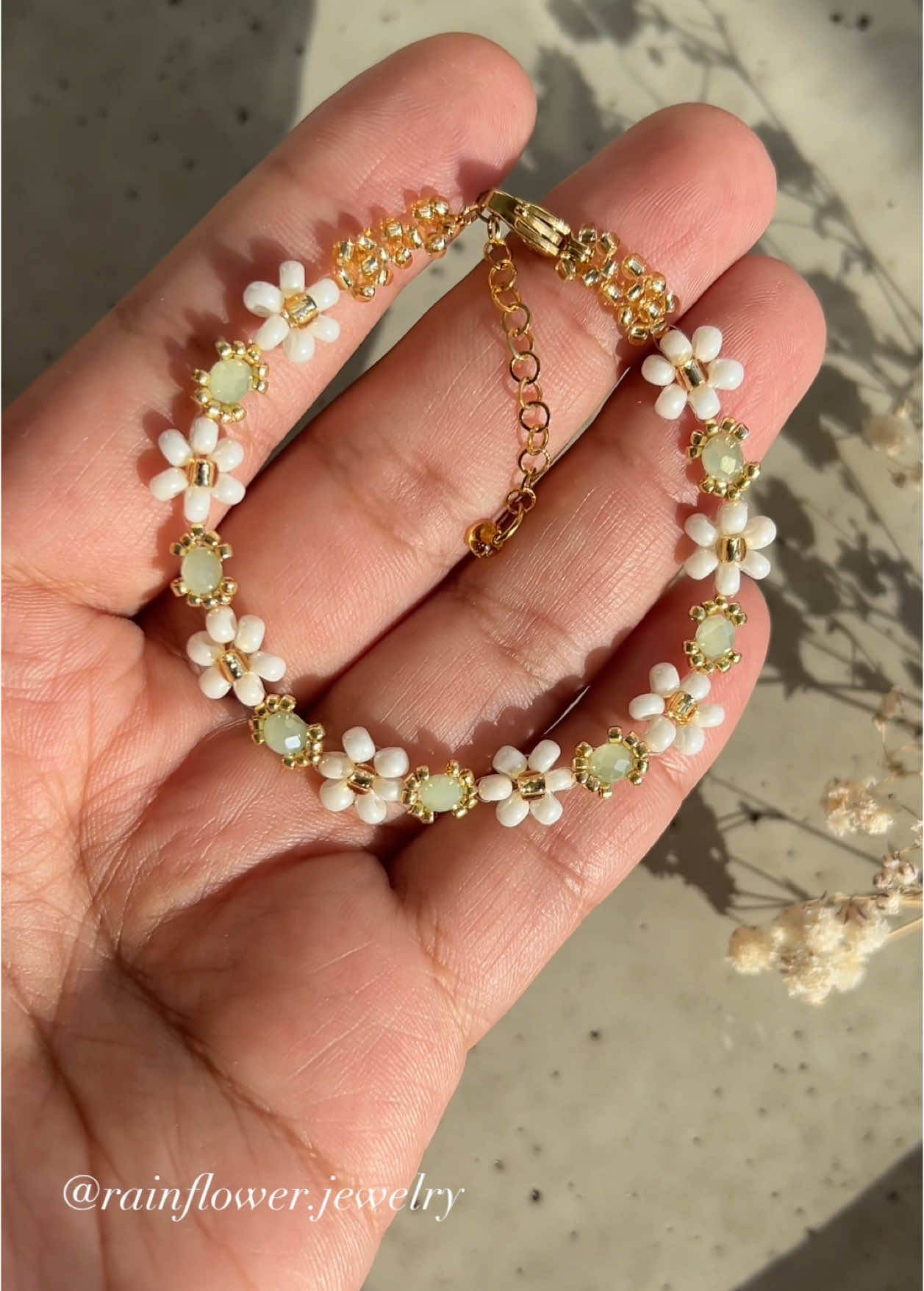 A post by @rainflower.jewelry on TikTok caption: This bracelet gives me the feeling of true spring—when the snow is gone, and the first hints of green start to appear🌱🤍 Now available in my shop with free shipping! Link in bio!✨ #springjewelry #floralbracelet #handmadeaccessories #beadedjewelry #bohochic #aestheticfashion #braceletstack #springawakening #natureinspired #cottagecorevibes #SupportSmallBusiness #trendyjewelry #viralfinds #fyp #musthaveaccessories #freeworldwideshipping 