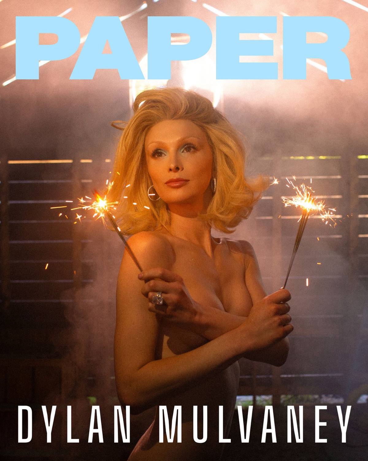 A post by @dylanmulvaney on TikTok caption: 2025 has been the most beautifully complicated year of my life. I have never felt so confident in my body, my voice, my womanhood, all while America tries to strip me of those very things. So what’s left underneath? A woman 🇺🇸❤️ @PAPER Magazine #papermag #coverstory #paperdoll #trans 