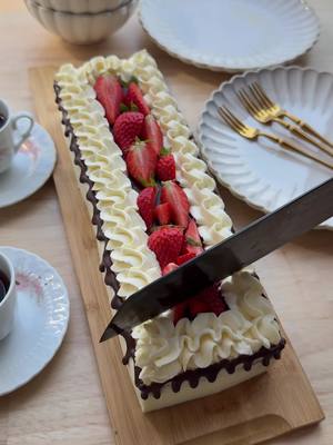 A post by @kookmutsjes on TikTok caption: 20 MINUTES CHOCOLATE CAKE (NO BAKE) #food #recipe #chocolate #pie #cake #nobake #tasty #cream #quick #fy #fyp #foryoupage   CAKE 8 chocolate cakes (store-bought) CREAM 250 g mascarpone 50 g powdered sugar 8 g vanilla sugar (1 packet) 16 g whipped cream stabilizer (2 tbsp) 400 ml heavy cream GANACHE 40 ml heavy cream 40 g dark chocolate TOPPING strawberries Place the mascarpone, powdered sugar, vanilla sugar, and whipped cream stabilizer in a deep bowl. Mix until smooth. Gradually add the heavy cream and mix until stiff. Transfer the cream into a piping bag. Remove the chocolate cupcakes from their packaging. Pipe a thin layer of cream onto a serving tray. Take one chocolate cake, spread a layer of cream on top and put it on the layer of cream. Repeat this for the rest and place the cakes next to each other in a straight row. Pipe a layer of cream over the cakes and smooth it out evenly. Heat 40 ml of heavy cream in a small saucepan until just below boiling. Remove from heat and add the chopped dark chocolate. Let it sit for 1 minute. Stir until smooth and glossy. Transfer the ganache into a piping bag. Pipe the ganache along the sides of the cake stack to create a drip effect. Pipe decorative dollops of cream along the top edges. Pour the remaining ganache in the center. Garnish with fresh strawberry pieces.