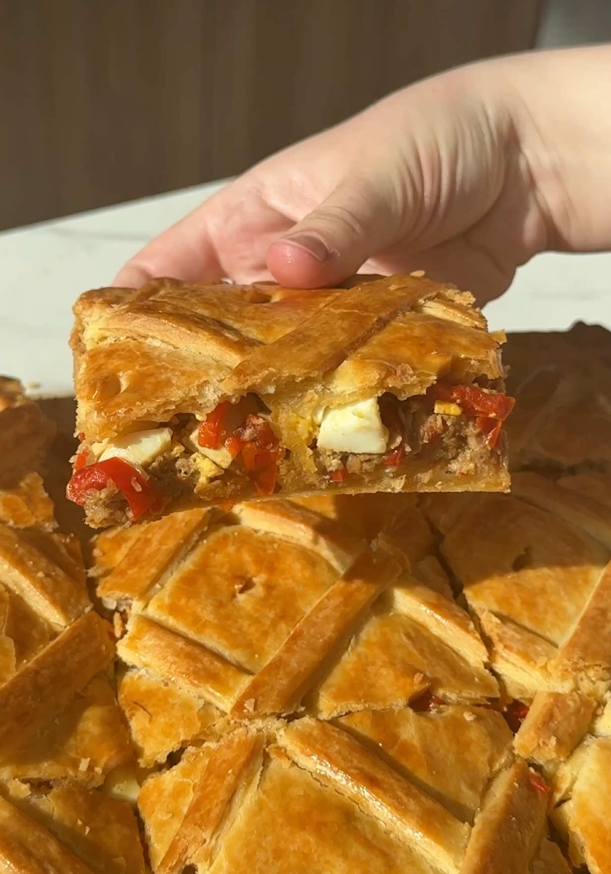 A post by @lasrecetasdesimon on TikTok caption: EMPANADA GALLEGA🇪🇸: Un clásico para semana santa ✨ • Ya se vienen las Pascuas y lo más clásico es comer mucho pescado, sobre todo atún✨ por eso, nosotros quisimos hacer una rica empanada gallega 😉 • 𝕀𝕟𝕘𝕣𝕖𝕕𝕚𝕖𝕟𝕥𝕖𝕤 Relleno: • 100ml Aceite de oliva 🫒  • 3 Cebollas🧅 • 2 Morrones Rojos • 1cda cucharada de Pimenton y Sal🧂 • 2/3 Latas de Lomitos de Atún 🐟 • 𝕀𝕟𝕘𝕣𝕖𝕕𝕚𝕖𝕟𝕥𝕖𝕤 Masa: • 700g de Harina 🌾 • 1 huevo 🥚  • 290ml Agua 💧  • 115ml Aceite de la cocción+ 135ml de aceite para completar (250ml totales) • 1cda de Sal y Polvo de Hornear 🧂 • Completá el relleno con huevos duros 🥚y morrones, y pincelá bien la masa con huevo🖌️ para que salga bien dorada y super crocante. Para los españoles una empanada y para nosotros una tremenda tarta ideal para estos días 🙌🏻 • #empanadagallega #atun #tarta 