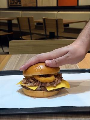 A post by @burgerkingbr on TikTok caption: Sanduíche no pão de brioche, com hambúrguer de carne bovina grelhado no fogo, 2 fatias de queijo sabor cheddar, carne de costela bovina desfiada, cebola crispy, 3 anéis de onion rings e maionese.  É tudo que a gente precisa pra fechar a semana no jeito!