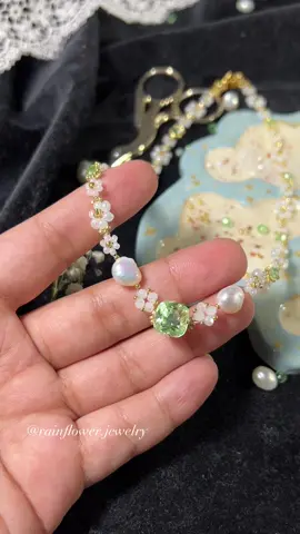 A post by @rainflower.jewelry on TikTok caption: Dainty necklace with a sparkling green stone is now available with free worldwide shipping🤍🌱✨ Tap the link in bio to order💫 #daintyjewelry #greenstone #beadednecklace #floralnecklace #handmadeaccessories #springjewelry #aestheticjewelry #fyp #trendingnow #jewelrytok #smallbusinesslove #supporthandmade #freeworldwideshipping #giftideas #bohojewelry 