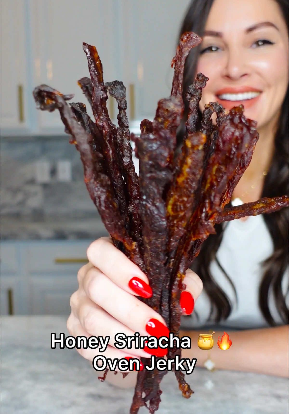 A post by @chefgenevieve on TikTok caption: Sweet and Spicy Oven Beef Jerky. This high protein snack is perfect for on the go and can be stored in an airtight container up to one month. You can substitute regular honey with keto honey if on a low carb diet.  Nutrition per slice: (Using regular honey)  85 calories, 10g protein, 5 net carbs, 2.8g fat  (Using keto honey) 73 calories, 10g protein, 0 net carbs, 2.8g fat Ingredients: 2lbs flank steak, sliced thin (1/8th inch thick) 1/2 cup sriracha  1/2 cup honey (or keto honey) 2 tsp garlic salt 30-35 wooden toothpicks  Directions: Combine all ingredients and marinade for four hours.  Place a toothpick through the top of each slice. Place a foil line sheet pan on the bottom rack of your oven to catch dripping.  Place the toothpicks up and over the top rack, leaving space in between each slice of beef. Bake in a 170° oven with the door slightly open to allow air to vent. Once your jerky is firm, but still slightly pliable, it’s ready.  Remove toothpicks and store airtight container for up one month in the pantry or in the fridge for up to 3 months.  Tip: Freeze beef for 40 minutes to firm to allow more precise slicing.  Enjoy! #homemadejerky #ovenjerky #beefjerky #highproteinsnack #sweetandspicy 