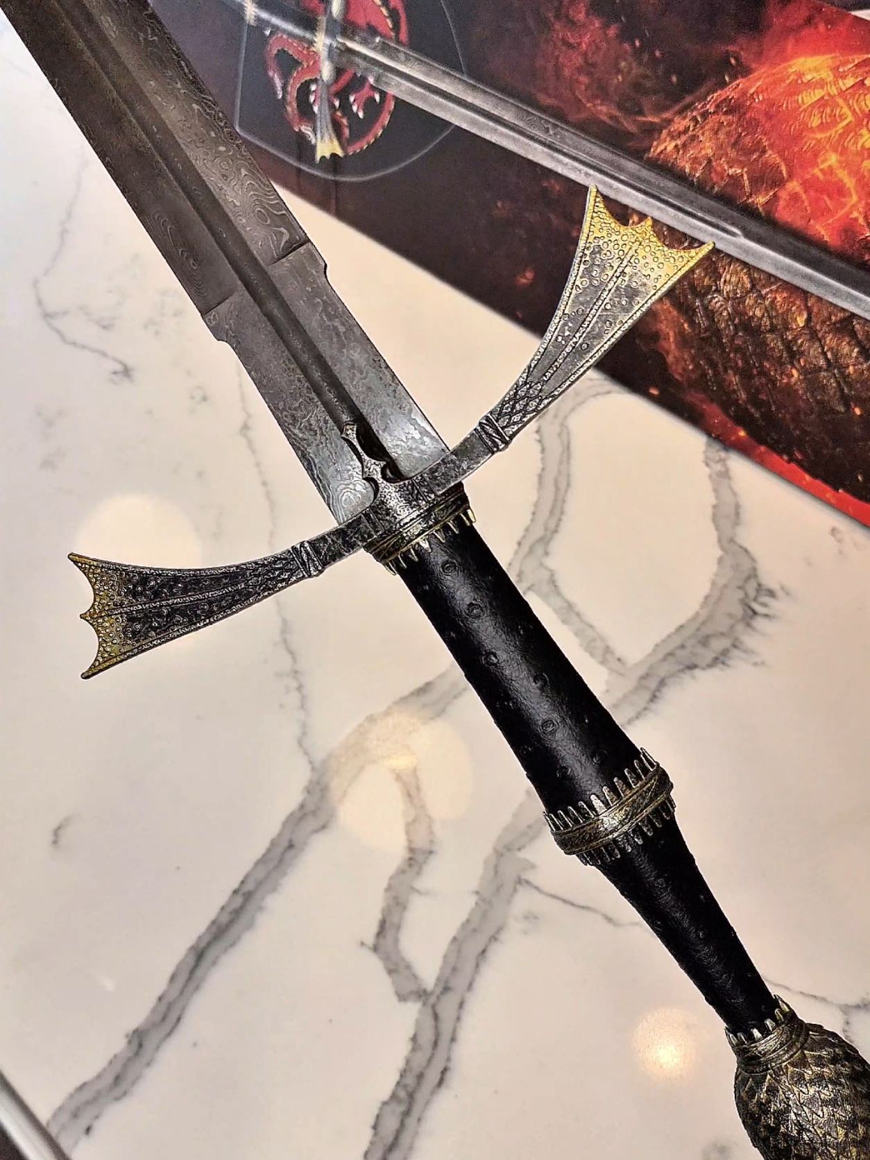 A post by @nomad.props on TikTok caption: dreams didn't make us kings. dragons did. 🐉 #unboxing #darksister #daemontargaryen #sword #damascussteel #houseofthedragon 