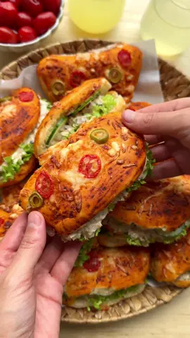 A post by @kookmutsjes on TikTok caption: PIZZA BREAD WITH TUNA SALAD #food #recipe #pizza #bread #tuna #salad #tasty #fy #fyp #foryoupage DOUGH 275 ml lukewarm water 7 g instant yeast (1 tablespoon or 1 sachet) 12 g honey 40 ml olive oil 500 g flour (all-purpose) 8 g salt (1⅓ teaspoons) 0.5 g Italian seasoning TOMATO SAUCE 40 g tomato paste 50 ml water 0.5 g Italian seasoning TOPPING grated cheese green olives, sliced cherry tomatoes, sliced TUNA SALAD 70 g red onion (1 red onion) 75 g pickles 10 g capers 280 g canned tuna (2 cans, in sunflower oil) 140 g mayonnaise EXTRAS lettuce cucumber Instructions: Put the lukewarm water, yeast, and honey in a large bowl. Mix well and let sit for 5 minutes. Add the olive oil and mix well. Add the flour, salt, and Italian seasoning. Knead for 10–12 minutes until smooth. Cover and let rise for 1 hour or until doubled in size. For the tomato sauce, mix the tomato paste, water, and Italian seasoning until smooth. Deflate the dough and divide it into 12 equal portions, about 70 grams each. Shape into balls. Roll each ball into a circle about 13 cm in diameter and fold it in half. Place the dough on a baking tray lined with parchment paper. Spread each piece with tomato sauce and top with grated cheese, olive slices, and cherry tomato slices. Let the dough rise for 30 minutes, or until doubled in size. Bake the dough in a preheated oven at 200°C (392°F) for 12–18 minutes until golden brown. Meanwhile, finely chop the red onion and pickles. Drain the tuna. In a bowl, mix the red onion, pickles, capers, tuna, and mayonnaise into a creamy salad. Open the bread and fill with lettuce, cucumber, and the tuna salad. Tips: Use lukewarm water (approx. 37 – 40°C / 98 – 104°F) to activate the yeast properly. Too hot will kill the yeast, too cold will slow down rising. Drain the tuna well to avoid a watery salad.