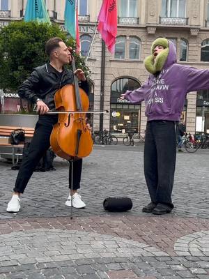 A post by @jodokcello on TikTok caption: Wait for it 🔥😍 I was playing Cello in the city when suddenly superstar @nemothingsss  came by and asked if I could play the Song "The Code", it was an incredible moment 😍✨️ #esc #eurovision #eurovisionsongcontest #nemo #music #love #viral 