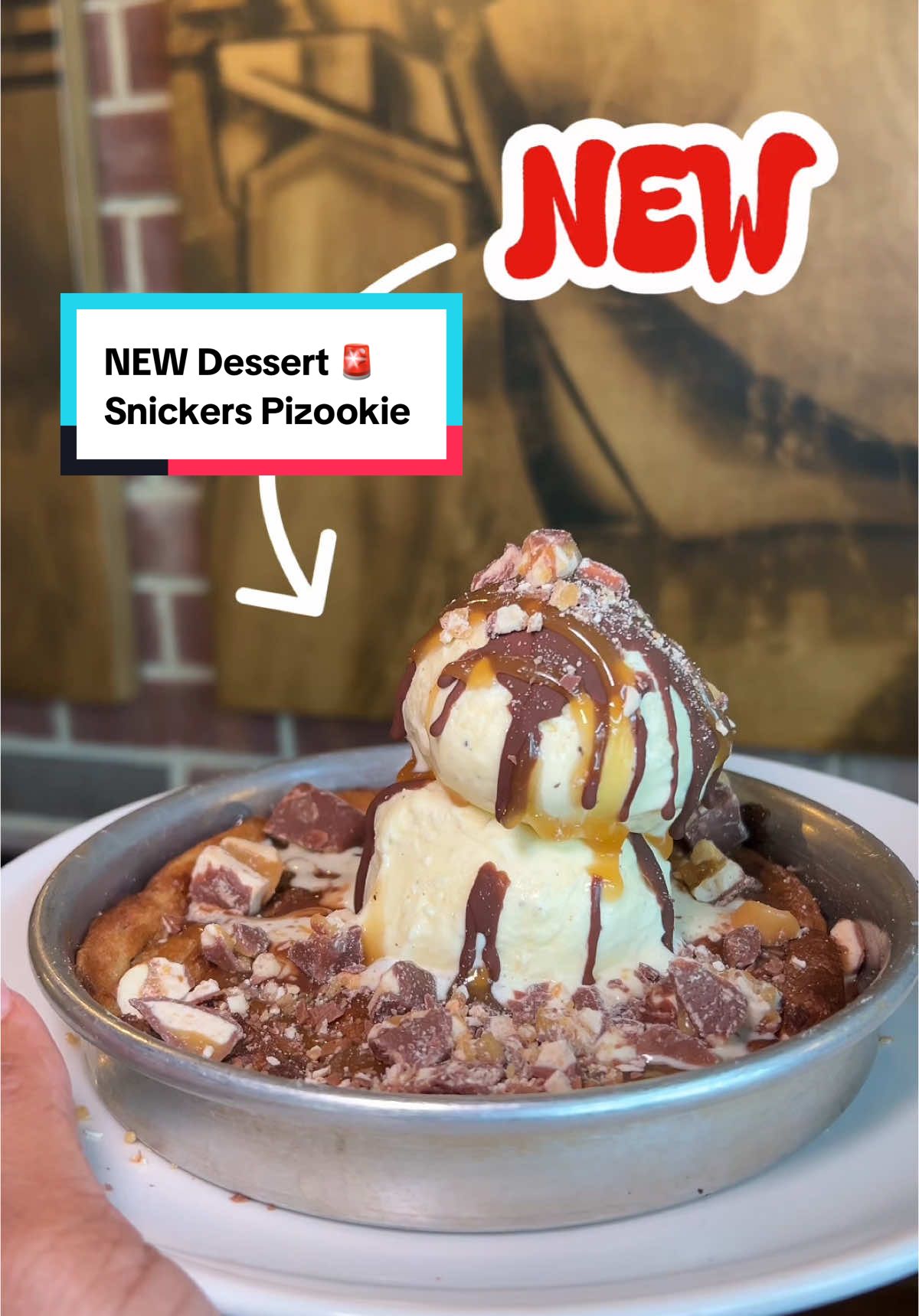 A post by @dasseats on TikTok caption: Y’all... I was not myself 😭 hoodie on & HANGRY. AD | Turns out all I needed was @bjsrestaurants NEW @snickers Pizookie!! It’s a brown sugar cookie with Snickers chunks, caramel, AND even a chocolate shell over the ice cream.  Run to your nearest BJs Brewhouse for your new favorite sweet tooth fix   #bjspartner #bjspizookie #snickers #dmvfoodie #dmvdesserts 