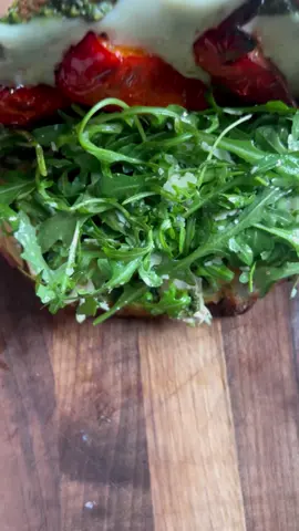 A post by @_lacebakes_ on TikTok caption: Pesto Chicken Melt. This is one of the recipes from my cookbook, but I’m sharing it below so everyone can try it! 🌿 Ingredients  2 large slices of bread, (I used the Easy Dutch Oven Bread from book) Melted butter for brushing onto bread Finely grated Parmesan  3 Tablespoons basil pesto (pesto recipe also in my book!) 2-3 slices provolone or mozzarella cheese 1 roasted or grilled chicken breast 1/2 red bell pepper, roasted Handful arugula Drizzle of extra virgin olive oil Tiny squeeze of lemon Parmesan shavings Method  Preheat the oven to 200°C (400°F). Place the chicken breast on a small baking tray and drizzle with extra virgin olive oil, then season with salt and pepper. Bake for around 20 minutes, or until the juices of the chicken run clear. Meanwhile, lightly coat the red pepper slices with extra virgin olive oil and season with salt and pepper. Add them to the tray with the chicken for the final 12 minutes of roasting time. When the chicken and peppers are nearly finished baking, preheat a large frying pan over a medium heat and coat with a drizzle of extra virgin olive oil.   Brush each slice of bread with melted butter and press the grated Parmesan into the butter. Spread the interiors of the bread with pesto. Lay the cheesy sides of the bread down into the preheated pan and top one side of the pesto covered bread with cheese and the other with the chicken. Add a bit of extra pesto to the top of the chicken.  Cook over a medium heat until the cheesy crust is golden and crispy and the cheese inside has melted.  While it’s cooking, mix up the salad. Toss together a handful of arugula, a drizzle of extra virgin olive oil, a tiny squeeze of lemon and Parmesan shavings. Add the salad and roasted red bell peppers to the sandwich when it’s finished cooking. Enjoy!  #sandwich #pestochickensandwich #foodporn #asmrcooking #asmr #sandwichrecipe #pestorecipe