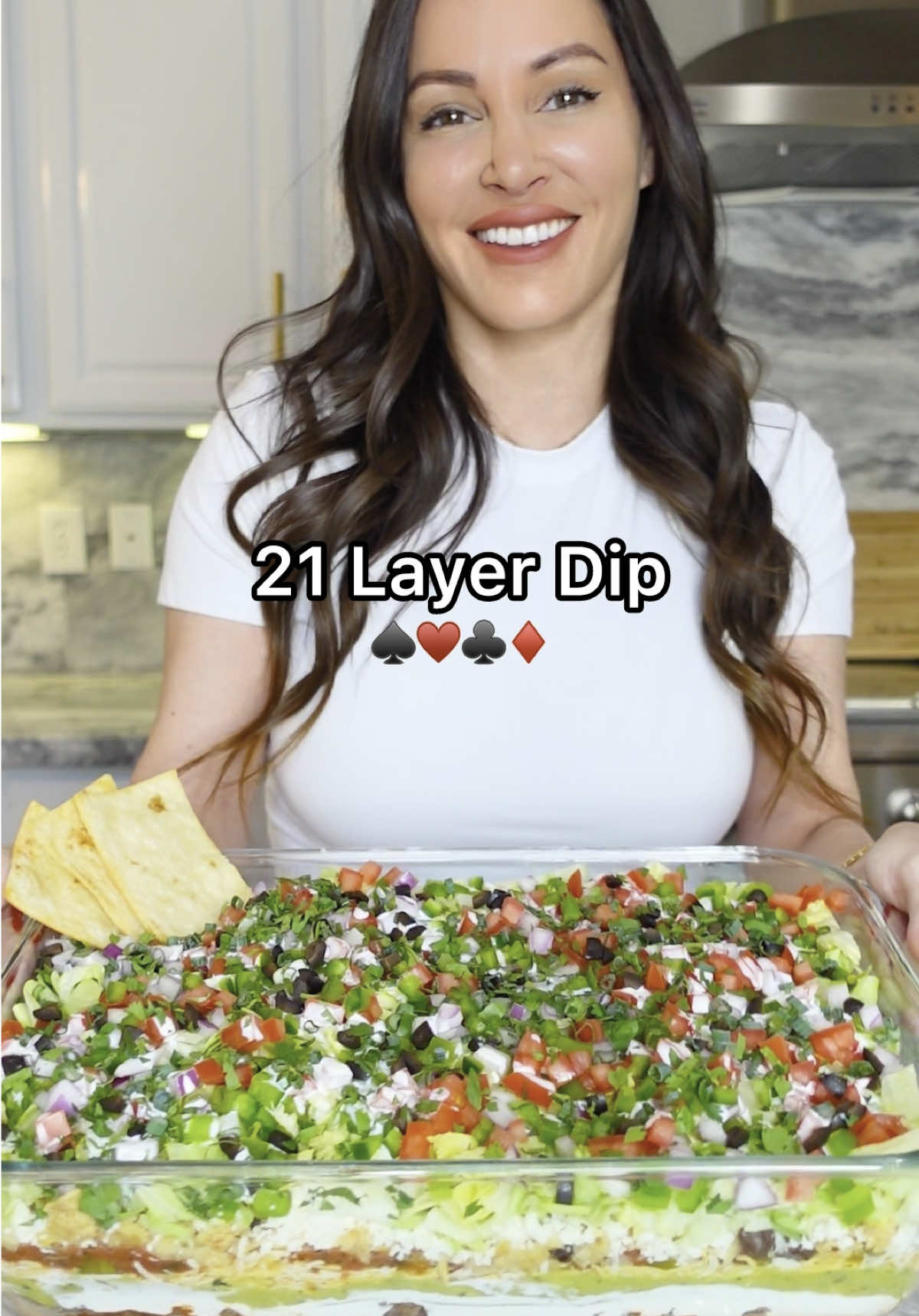 A post by @chefgenevieve on TikTok caption: Ever heard of a 21-layer dip? This one’s stacked high with flavor and served with homemade tortilla card chips - perfect for game night! Deal yourself a bite and let me know if you’d go all in on this dip! Inspired by @Cafe Casino  21 layer dip: Ingredients: 1. 1 can refried beans 2. 1lb cooked ground beef 3. 1 packet taco seasoning 4. 2 cups sour cream 5. 2 cups guacamole 6. 2 cups shredded cheese 7. 1 small can diced jalapeños 8. 2 cups salsa 9. 1/2 can sweet corn 10 1/2 can drained and rinsed black beans  11. 2 cups crumbled tortilla chips 12. 1/2 pack queso fresco 13. 2 cups shredded iceberg lettuce 14. 1 green bell pepper, diced  15. 1/4 red onion, diced  16. 3 Roma tomatoes, diced  17. 1/4 cup Crema Mexicana 18. 1 fresh jalapeño, diced  19. 1/4 cup black olives, diced  20. 1/4 cup green onion, sliced thin 21. 1/4 cup cilantro, chopped Layer all ingredients then refrigerate until ready to use.  Card Shaped Tortilla Chips: Ingredients: 5 flour tortillas (burrito size) Salt Stack flour tortillas, cut through the center vertical and horizontal then into playing card shapes. Lay your tortilla cards down on a large sheet pan and spray both sides with avocado oil.  Sprinkle on some salt and bake in a 400° for 20 minutes (check at 15 minutes as ovens may vary). They should be crisp and golden. Enjoy! #21LayerDip #PartyRecipes #HomemadeChips #GameNightRecipes #CafeCasinoPartner