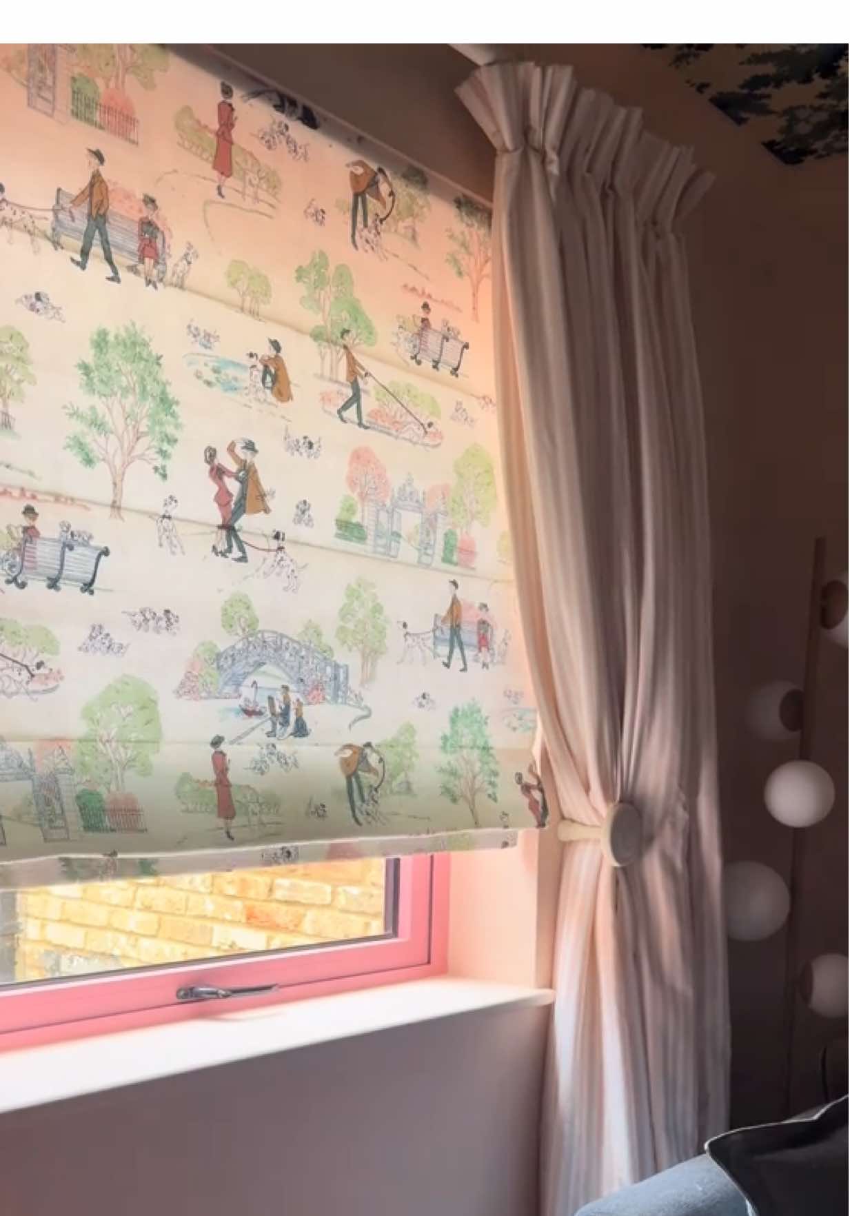 A post by @thiscolourfulnest on TikTok caption: W h i m s i c a l  w i n d o w 🌳🌷🐾 • Ad. After a year of nothing, I have FINALLY styled the snug window ✨ @Blinds 2go whisked me away last month to catch a glimpse of their new Disney Home x Sanderson 1860 collection.  From nostalgic illustrations to comforting scenery, you were lead into a world of classic Disney storytelling and childhood memories.  The Disney 101 Dalmatians design was my favourite, with the soft green and rose colour palette! I love the romantic tale that features in the scene… and this immediately felt ideal for our family snug, where the movies are forever playing 🍿  Teamed with the Tiger Stripe fabric in Blush, the layering of the designs is romantic and cosy, especially with the added thickness and weight of the thermal lining! Something we still require in our old cottage.  The Roman Blind and single curtain provide a timeless window dressing, perfect for closing out the light for daytime movies and cosy moments, to half drawn late afternoons reading our favourite stories - the power of a window dressing is unmatched! And I can say, this finishing touch has been just what the room was crying out for 🩷✨🎀 The biggest bonus? The blind was no-drill installation and powered by the Smartview app, it can be remotely drawn or opened and you can even pick your favourite mood’s for it to respond to at the click of a button! Clever, very clever… 💫 #blinds2go #disneyhome #sanderson #apartmenttherapy #inmydomaine #pinkaesthetic #moreismoredecor #myhomevibe #barbiecore #colourfulhomevibe #kitchendecor #cottagecore #homedecor #pinterestaesthetic #myhome #myhomedecor #myhometrend 