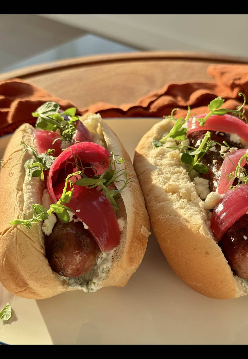 A post by @giallolovesitaly on TikTok caption: Hot dogs with a gourmet twist🌭! Luganega sausage, creamy yogurt sauce, sweet-and-tangy raspberry onion, and crumbled feta, topped with fresh pea shoots for the perfect finish🌱🧅🧀 Will you try it?😋 Ingredients for the Sandwich: 4 hot dog buns 4 long Italian sausages (such as luganega), about 14 oz (400 g) 1 cup (7 oz / 200 g) feta cheese, crumbled Extra-virgin olive oil, as needed For the herb sauce: ¾ cup + 2 tablespoons (7 oz / 200 g) plain yogurt 1 tablespoon (0.5 oz / 15 g) lemon juice Salt, to taste Chives, to taste Parsley, to taste For the Raspberry Onion: 1 red onion 7 tablespoons (3.5 oz / 100 g) white vinegar 1½ tablespoons (0.7 oz / 20 g) sugar ¾ cup + 2 tablespoons (7 oz / 200 g) raspberry juice (or 2⅔ cups (14 oz / 400 g) fresh raspberries) Salt, to taste Pepper, to taste To garnish: Pea shoots, to taste #giallolovesitaly #hotdog #italianrecipe #foodtok