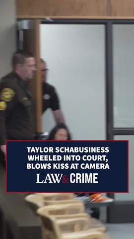 A post by @lawandcrime on TikTok caption: A shackled Taylor Schabusiness was wheeled into court on Tuesday for a brief hearing in her battery case. Schabusiness blew a kiss to the camera as she was wheeled in. The convicted killer is accused of attacking a prison guard in July 2024. A trial date was set for October 27th. #Trial #Hearing #TrueCrime #Court #CaughtonCamera #Battery