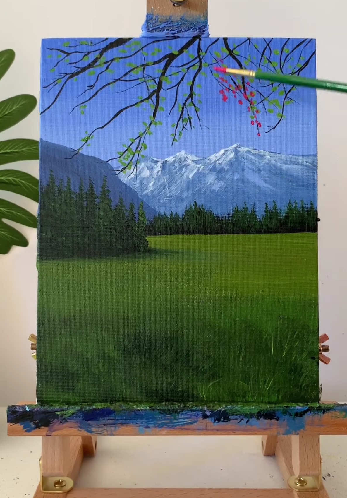 A post by @fenonart on TikTok caption: • @iffaizzn The mountains in the distance stand tall in the embrace of green trees 🌄 #TakeYouIntoThePainting #OilPainting #NatureArt #MountainScenery #HandPainted #ArtReel #LandscapePainting #MiyazakiInspired #CreativeJourney #artistoninstagram #fyp