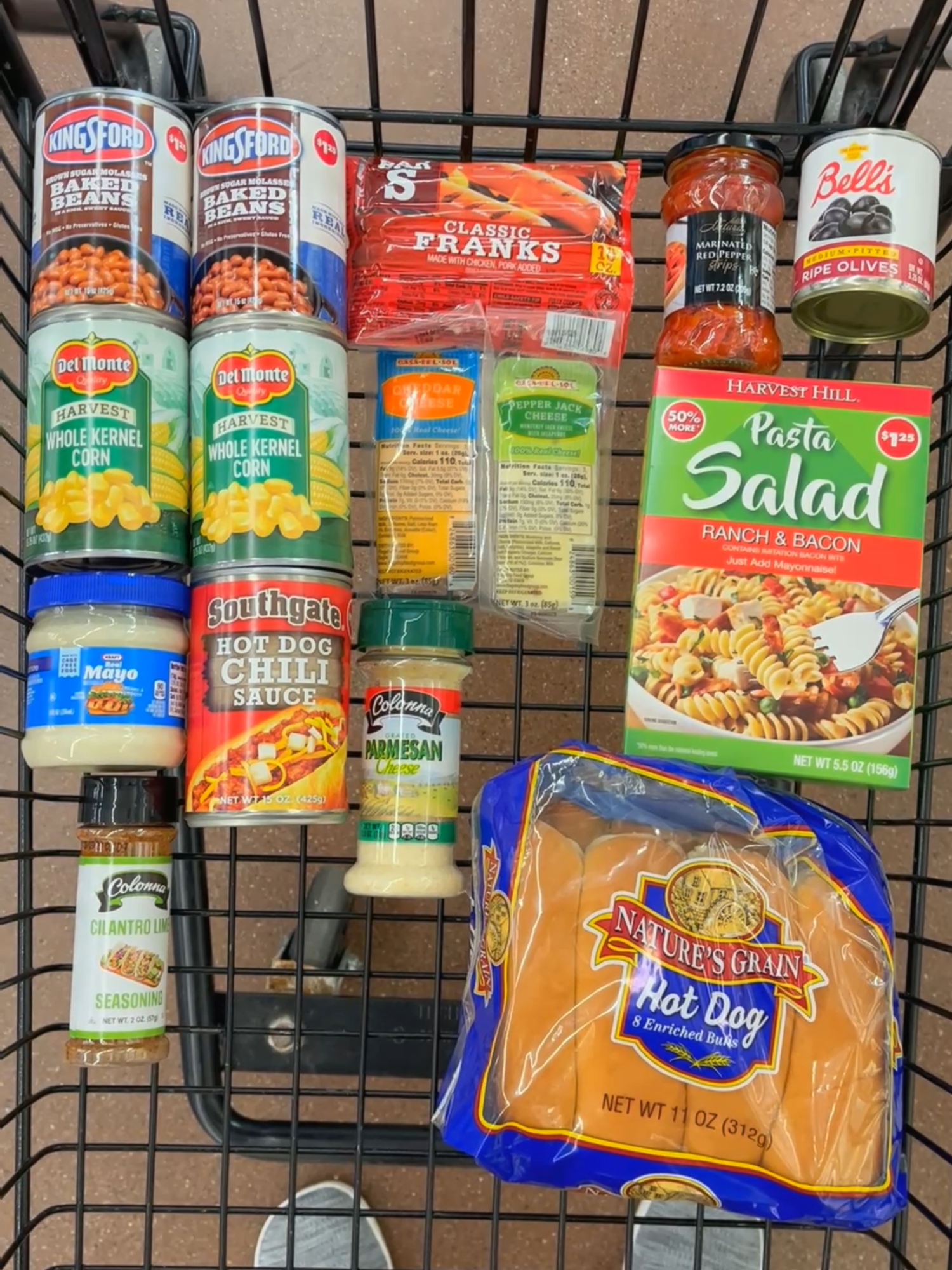 A post by @dollartreedinners on TikTok caption: I had a $20 budget to pull off a summer BBQ for four, and I grabbed everything from @Dollar Tree! This is perfect for a low key summer hangout, and yep...I even had a dollar to spare! Shopping list: Hot Dogs (1 pack, classic, chicken or turkey) $1.25 Hot Dog Buns $1.50 Hot Dog Chili $1.25 Cheddar Cheese $1.25 2 cans baked beans $2.50 2 cans corn $2.50 Mayonnaise $1.25 Cilantro Lime Seasoning $1.25 Parmesan Cheese $1.25 Pasta Salad Mix (Creamy Parmesan or Bacon & Ranch) $1.25 Black olives $1.25 Marinated Red Pepper Strips $1.25 Total cost $19! I turned it all into chili cheese dogs, baked beans, Elote style corn salad, and a pasta salad with extra mix ins, a full summer spread from just one cart. Stay tuned for the full recipes in my next video. #dollartreepartner #dollartreedinners #summerbbq #budgetmeal #cookoutonabudget #frugalfood #backyardbbqonabudget #elotesalad #chilicheesedogs #dollartreegroceryhaul #summeronabudget