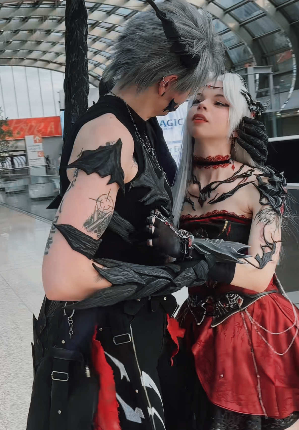 A post by @teacakecos on TikTok caption: when your cosplays are fragile, so you have to gently cradle each other 🥺❤️🖤 @Lena_Kuroi / レナくろい #loveanddeepspace #mccosplay #dokomi #dokomi2025 #sylusloveanddeepspace #syluscosplay #lads #germancosplay #loveanddeepspaceedit 