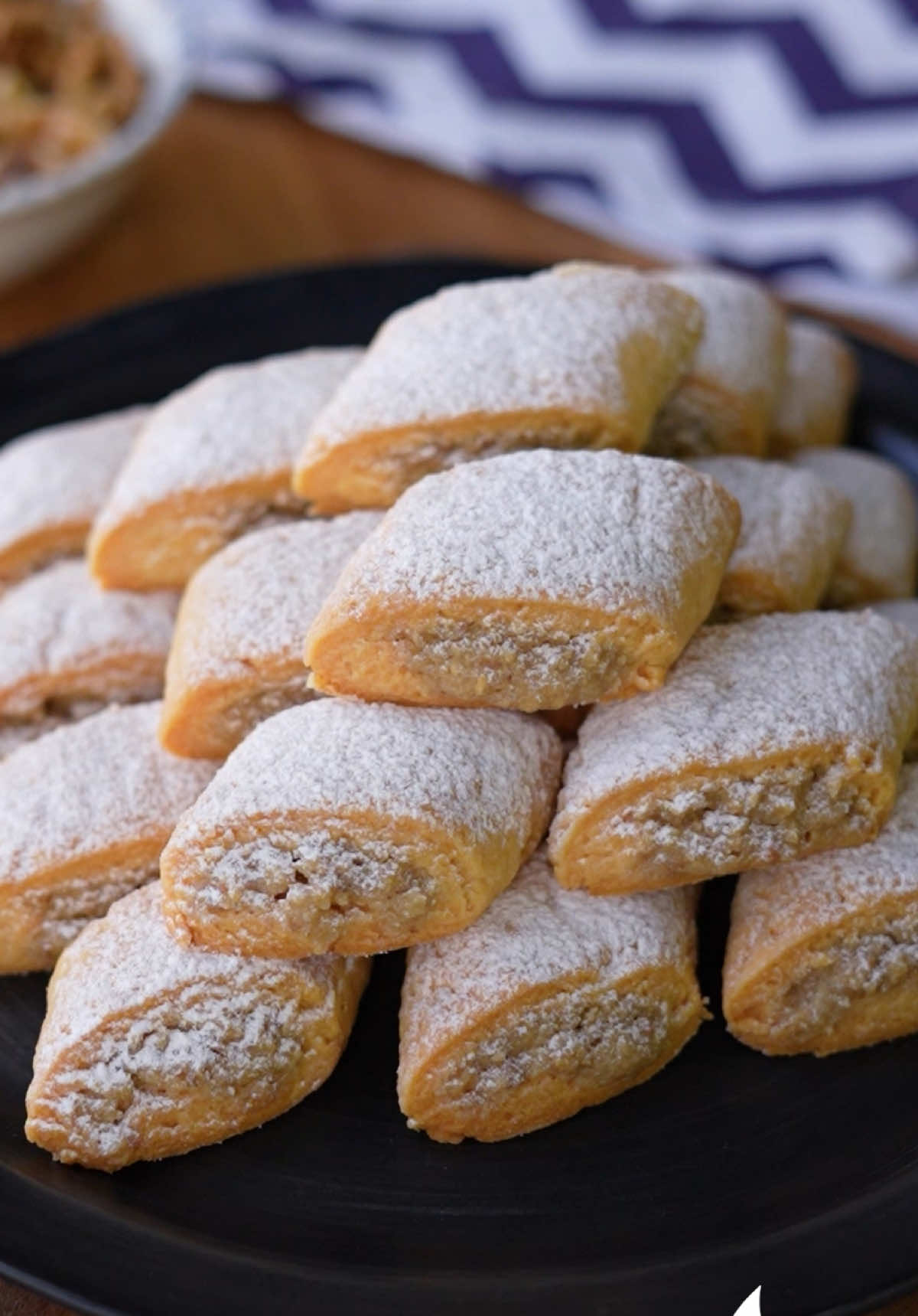 A post by @nefisyemektarifleri on TikTok caption: En İyi Tahinli Kurabiye Tarifi 🥇😋🍪 Kıyır kıyır bu efsane kurabiye tarifimizi kimler deneyecek bakalım? 🤩 Malzemeler Hamuru için; 125 g tereyağı Yarım su bardağı sıvı yağ (100 ml) Yarım su bardağı yoğurt 1 adet yumurta sarısı 1 paket kabartma tozu 3 su bardağı un İç dolgusu için; 1 su bardağı tahin (200 ml) 1 su bardağı ceviz 1,5 su bardağı şeker Üzeri için; Pudra şekeri Hazırlanışı İç dolgusu için tahin, şeker ve cevizi güzelce karıştıralım. Hamuru için oda sıcaklığındaki tereyağı, sıvı yağ, yumurta sarısı ve yoğurdu bir spatula ile karıştıralım. Unun bir kısmını ve kabartma tozunu da ilave edip hamuru yoğuralım. Hamuru un serptiğimiz tezgaha alalım ve üç eşit parçaya bölelim. Parçalardan birini alarak rulo şekli verelim ve elimizle hafifçe bastırdıktan sonra merdane ile genişletip inceltelim. İsteğe bağlı kenardaki eğrilikleri bıçakla keserek düzeltelim. Tahinli iç harcı hamurun ortasına bolca yerleştirelim, nazikçe kıvırarak hamuru tekrar rulo şeklinde saralım ve verev şeklinde keselim. Pişirme kağıdı serdiğimiz fırın tepsisine aralıklı olacak şekilde yerleştirelim. Diğer hamura da sırasıyla aynı işlemleri uygulayalım. Kurabiyeleri önceden ısıttığımız 180 derece fırında fansız ayarda 20-25 dakika pişirelim. Kurabiyeler soğuduktan sonra pudra şekeri serperek servis edelim. Afiyet olsun! #nefisyemektarifleri #nefisyemektariflerinden #tarif #tarifler #bugünnepişirsem #food #cooking #recipe #recipetok #TiktokMutfağı