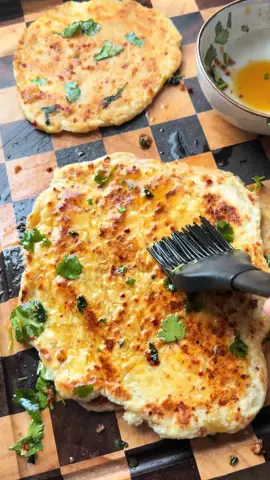 A post by @piaundhalloumi on TikTok caption: Hüttenkäse Knobi Pfannenbrot 🧄 Dieses Rezept hab ich bei @melissasfoodspace gesehen und musste es sofort ausprobieren. Wirklich super lecker zum Dippen & als Beilage. Zutaten (für 4 kleine Fladen):     200 g Hüttenkäse     180 g Dinkelmehl     ½ TL Backpulver     1 TL Salz     1 EL Olivenöl (optional) Zum Bestreichen:     2–3 Knoblauchzehen, gepresst     1–2 EL Butter, geschmolzen     Koriander (frisch oder getrocknet)     Chiliflocken     Salz Zubereitung:     Teig kneten: Hüttenkäse, Mehl, Backpulver und Salz in einer Schüssel zu einem glatten Teig verkneten.     Fladen formen: Den Teig in 4 Portionen teilen, jede Portion rund ausrollen.     Braten: Eine Pfanne auf niedriger bis mittlerer Stufe erhitzen und die Fladen nacheinander ohne Fett ausbacken – pro Seite ca. 2–3 Minuten, bis sie leicht gebräunt sind.     Bestreichen: Butter mit Knoblauch verrühren. Die heißen Fladen sofort damit bestreichen.     Verfeinern: Mit Koriander, Chiliflocken und etwas Salz toppen. #pfannenbrot #knoblauchbrot #hüttenkaserezept #naanbrot #beilage 