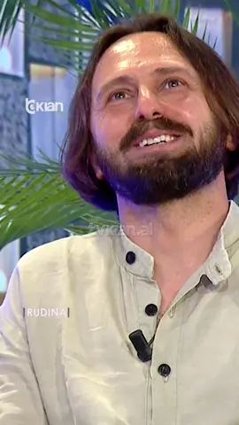 A post by @rtvklanofficial on TikTok caption: "‘O Zot!’ Pyetja e Rudinës që la të ftuarin pa fjalë" Kishim në këtë pjesë një pianist, improvizues, kompozitor dhe poliinstrumentist, një figurë eklektike në skenën muzikore shqiptare dhe ndërkombëtare. Ai është Robert Bisha dhe do të vijë në mbrëmjen e 14 qershorit në skenën e Teatrit të Operës dhe Baletit me një koncert të veçantë PAS 16 VITESH 𝐧ë 𝐩𝐢𝐚𝐧𝐨 𝐬𝐨𝐥𝐨 𝐦𝐞 𝐩𝐫𝐨𝐣𝐞𝐤𝐭𝐢𝐧 “𝐎𝐧 𝐭𝐡𝐞 𝐑𝐨𝐚𝐝”. Videon e plotë e gjeni në kanalin e YouTube ▶️ RTV KLAN #TvKlan #Rudina #Piano