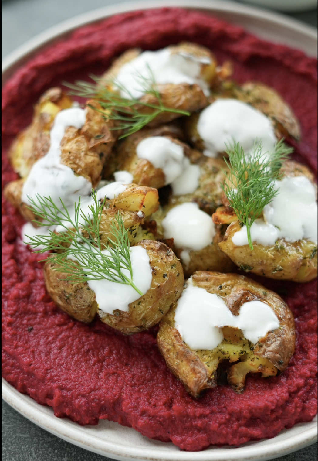A post by @nefisyemektarifleri on TikTok caption: Smash patatesler pancar mezesiyle buluştu, ortaya tam bir lezzet şöleni çıktı! 😋✨ Philips Çift Hazneli Airfryer sayesinde kısa sürede hazır olan bu pratik tarifi mutlaka deneyin! 😍 Üstelik sonrasında Airfryer’ın çıkarılabilir tüm parçalarını ister elde ister bulaşık makinesinde yıkayarak temizlemek de çok kolay! 🤍 @philipsevurunleriturkiye #Airfryer #ÇiftHazneliAirfryer #işbirliği Malzemeler Smash Patates için; 800 g baby patates 3 yemek kaşığı zeytinyağı 1 çay kaşığı kuru nane 1 çay kaşığı kuru kekik Yarım çay kaşığı karabiber 1 çay kaşığı tuz Pancar Mezesi için; 2 adet orta boy pancar 1 yemek kaşığı zeytinyağı (Pancarlar için) 1,5 su bardağı haşlanmış kuru fasulye 2 yemek kaşığı tahin 1 limonun suyu 1 adet sarımsak 1 yemek kaşığı zeytinyağı 1 çay kaşığı tuz Yarım çay kaşığı kimyon Yarım çay kaşığı karabiber Hazırlanışı Baby patatesleri 10 dakika kadar haşladıktan sonra bir bardakla ezip üzerlerine zeytinyağı ve baharat karışımından sürelim. Çift Hazneli Airfryer'ın ana haznesine patatesleri yerleştirelim. Airfryer'ın yan haznesine doğradığımız pancarları alalım ve üzerine zeytinyağını ekleyerek karıştıralım. Hazneleri yerleştirip patatesleri 180 °C’de 20 dakika, pancarları 30 dakika pişmeye bırakalım. Daha sonra pancarı, haşlanmış kuru fasulyeyi, limon suyu, zeytinyağı, tahin, sarımsak, tuz ve baharatları robottan geçirelim ve mezeyi servis tabağımıza alıp yaydıralım. Üzerine patatesleri de yerleştirdikten sonra çırpılmış yoğurt gezdirip dereotu ile süsleyerek servis edelim. Afiyet olsun! #nefisyemektarifleri #tarif #tiktokmutfağı #airfryertarifleri