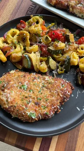 A post by @cookinginthemidwest on TikTok caption: Parmesan Garlic Chicken with Tortellini and Veggies made on the griddle!  INGREDIENTS 2 Zucchini, chopped  1 Red onion, sliced  1 heaping cup cherry tomatoes  Pepperoncinis, chopped Salt, pepper, garlic powder  19 oz bag frozen cheese tortellini  Italian dressing  Parmesan cheese 1 lb chicken breast Buffalo Wild Wings Parmesan Garlic 1 1/2 cups Italian style breadcrumbs  3/4 cup Parmesan cheese Dried parsley INSTRUCTIONS  For the veggies and tortellini, add all of the veggies to the griddle and season with salt, pepper, and garlic powder. Stir and cook until the vegetables are cooked. Add the bag of frozen tortellini with a little bit of water. Cover with a large griddle dome for a few minutes, or until the tortellini are tender.  Once the tortellini and veggies are cooked, pour some Italian dressing over them and stir well. Top with Parmesan cheese.  Cut the chicken breasts in half lengthwise to make them thinner. Pat the chicken breasts dry with paper towels. Add them to a bowl and cover in Buffalo Wild Wings Parmesan Garlic Sauce. Stir until the chicken is well coated in sauce.  Next, in a separate bowl or container combine the breadcrumbs and parmesan cheese. Dredge the chicken in the breadcrumb mixture making sure both sides are well breaded.  Heat a griddle over medium heat. Add some oil to the griddle and carefully lay the breaded chicken in the oil. Cook until golden brown and flip to cook the other side. Cook until both sides are golden brown and the chicken reaches an internal temperature of at least 165 degrees F. Once the chicken is fully cooked, you can lay the chicken out on paper towels to drain any extra grease.  I like to top the chicken with some Parmesan cheese and dried parsley! Enjoy!  *The pepperoncinis made the tortellini and veggies spicy! Use banana peppers instead, or completely omit them if you don’t want any spice!  #griddlerecipes #parmesangarlic #chicken #easyrecipes #dinner 