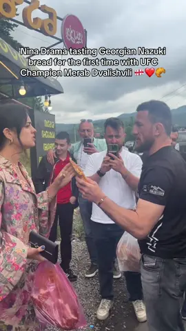 A post by @ninadrama on TikTok caption: Nina Drama tasting Georgian Nazuki bread for the first time with UFC Champion Merab Dvalishvili 🇬🇪❤️🥐 #UFC #ufc316 #merabdvalishvili #ninadrama #kickboxing #boxing #muaythai #muaythaifighter #muaythaifighter #taekwondo #jiujitsu #brazilianjiujitsu #jiujitsugrappling #jiujitsulifestyle #wrestling #wrestlingtiktok #wrestlingtok #fit #Fitness #grappling #karate #boxing #judo #seanomalley #georgia #georgian #tbilisi 
