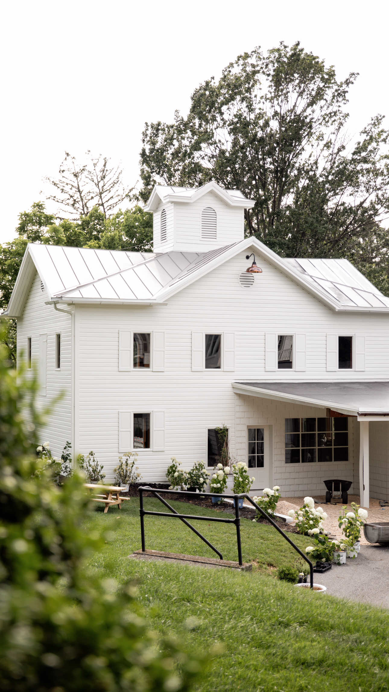 A post by @nabela on TikTok caption: Built in 1873. Reimagined with love in 2025. Today, I begin restoring our historic 153 year old carriage house — breathing softness into her dark exterior, painting it back to her original color, and slowly shaping her into a reflection of our family, our story and our forever home. 🤍 Would you like to see a Part 2?  #pocketsofpeace #design #exteriordesign #homedecor #transformation #renovation #garden #remodel #diy #summer 