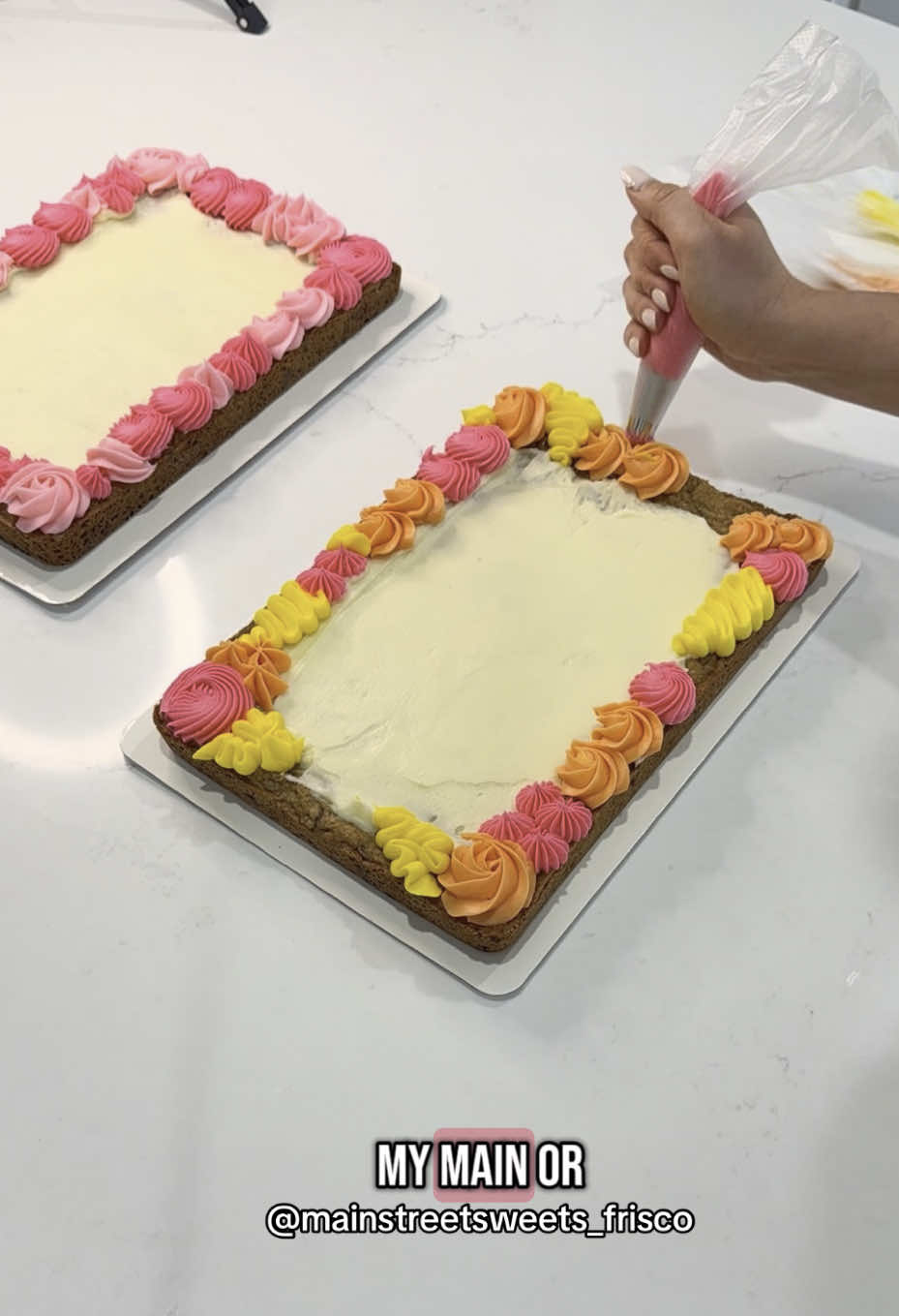 A post by @mainstreetsweets_frisco on TikTok caption: the message: 😠🙄😒👎 the video: 🤩💗⭐️🧡  #cookiecake #buttercream #pipingbuttercream #fyp #foryou 