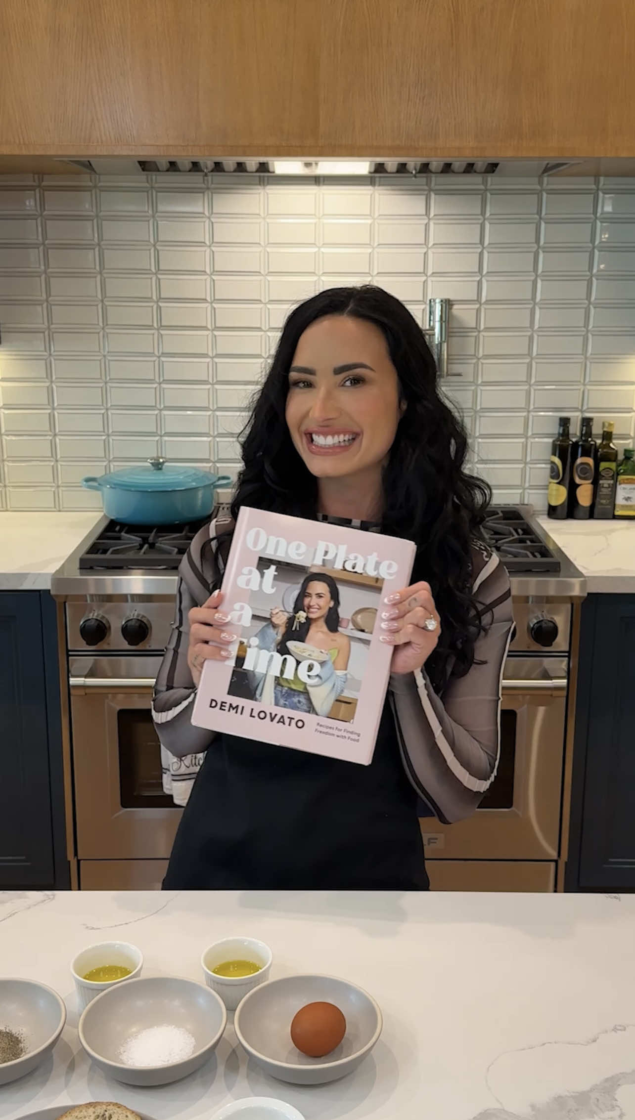 A post by @ddlovato on TikTok caption: I am so excited to announce my first cookbook: One Plate At A Time 🩷 Stepping into the kitchen and learning how to cook has been such an important part of my recovery and healing my relationship with food. This book is filled with simple, comforting recipes that have allowed me to reconnect with myself and find both freedom and joy in my kitchen – feelings I never thought I could experience. It has allowed me to see cooking as an act of love and kindness to myself and those in my life, and I hope this book can bring that same feeling into your home too.  One Plate At A Time will be yours March 31, 2026. You can pre-order the book at the link in my bio now!  And don’t worry, I’ve been cooking outside of the kitchen too… 😉