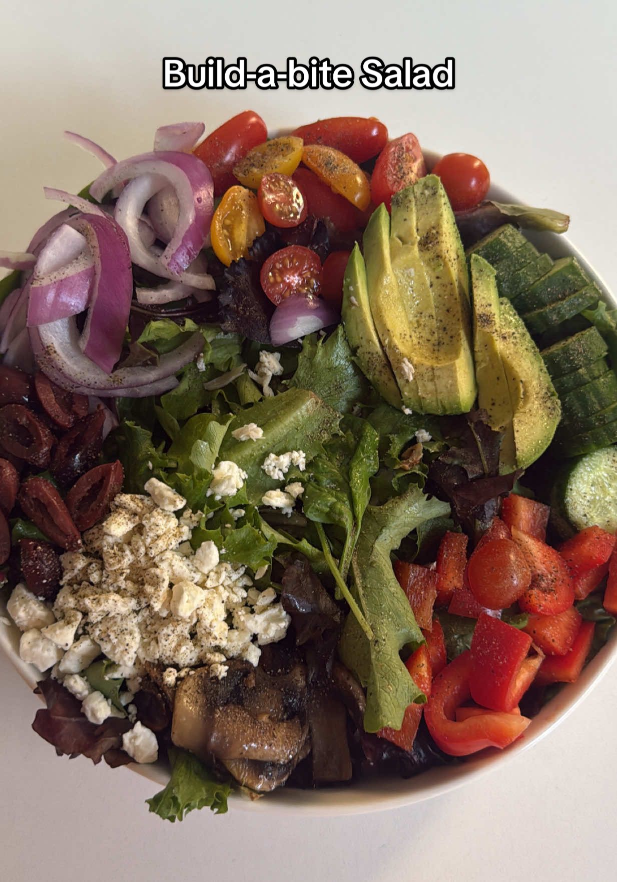 A post by @lebaneseangel22 on TikTok caption: Introducing my build-a-bite salad 🥗  🛒 INGREDIENTS: •Romaine lettuce – base layer, chopped •Spring mix lettuce – mix with romaine for volume + texture •Mushrooms – sauté in a splash of avocado oil until golden •Cherry tomatoes – sliced in half •Red onion – very thinly sliced so it doesn’t overpower •Kalamata olives – pitted + sliced in half •½ avocado – sliced (adds the creamy bite) •Red bell pepper – chopped for crunch and a splash of flavor  •Small cucumber – sliced for hydration + texture •Feta cheese – sprinkle for tangy creaminess •Protein of choice – I used shredded rotisserie chicken breast •Dressing – Primal Kitchen balsamic with avocado oil (super light, fresh & clean) •Salt & pepper – essential for flavor layering 🥣 THE TECHNIQUE: 1. Start with a large, round, flat bowl — this changes everything. The shape lets you lay ingredients next to each other without crowding. (Mine’s linked in my Amazon kitchen list.) 2. Lay down the lettuce first — half romaine, half spring mix.  3. Place each ingredient in its own section around the outer edges of the bowl. Think: color wheel vibes. 4. Season with salt and pepper right over the top. Let it sit a few minutes — this draws out flavor and softens raw veggies like onion. 5. Drizzle dressing over everything — just enough to lightly coat. 6. Add your protein LAST, right in the center (close enough to grab with every bite)  Don’t mix it!!!. You grab a little from each section with your fork so every bite is different 😍